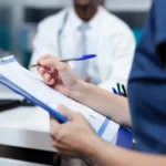 Profissional de saúde anotando em clipboard durante consulta médica, ilustrando a importância de um plano de saúde para autista.